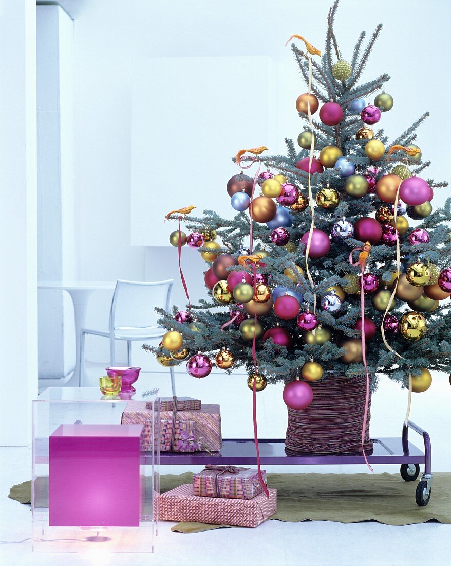 Christmas tree decorated with golden birds-of-paradise and baubles in deep pink, gold and silver