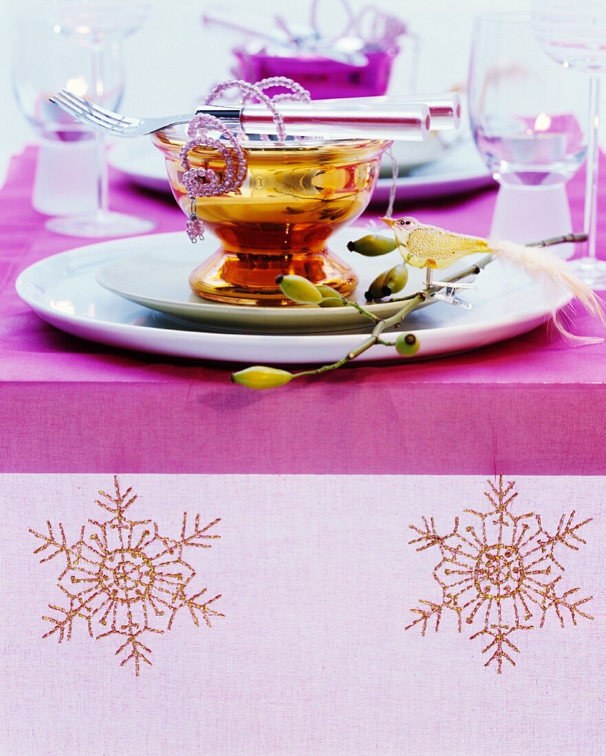 Weihnachtlich gedeckter Tisch mit besticktem Tischläufer und farbigen Silberglasschalen