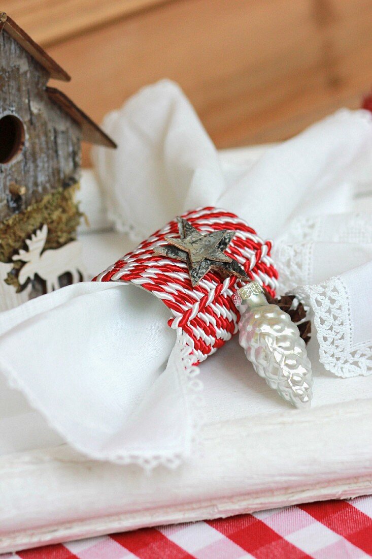 Selbstgebastelter weihnachtlicher Serviettenring aus rot-weißem Kordelband