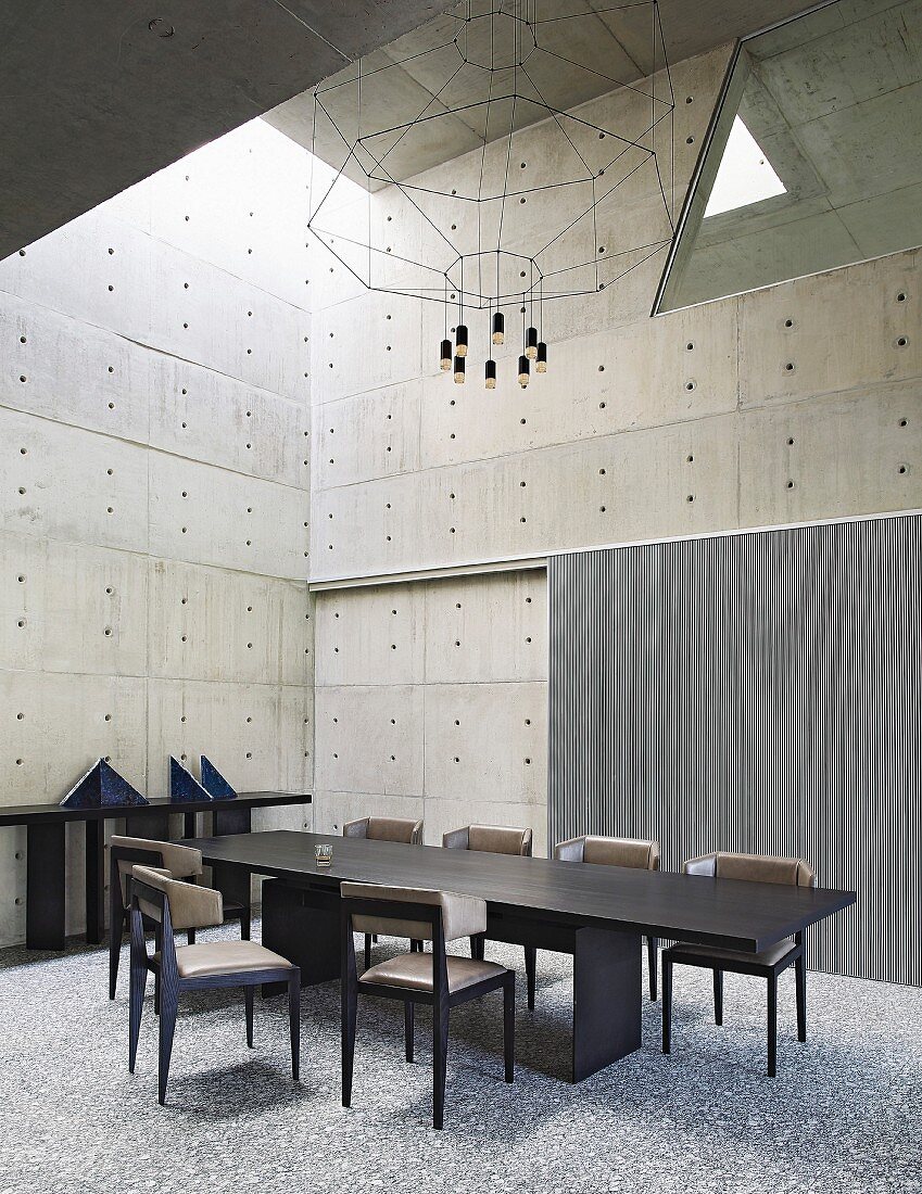 Geometrische Formen im Esszimmer mit Betonwänden und dunklen Möbeln