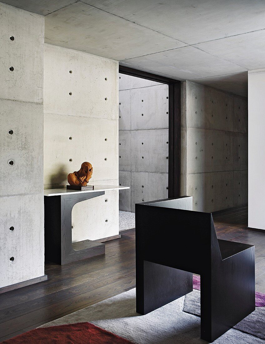 Raum mit dunklem Holzboden, moderner Kunst und Sichtbeton an Wänden und Decke