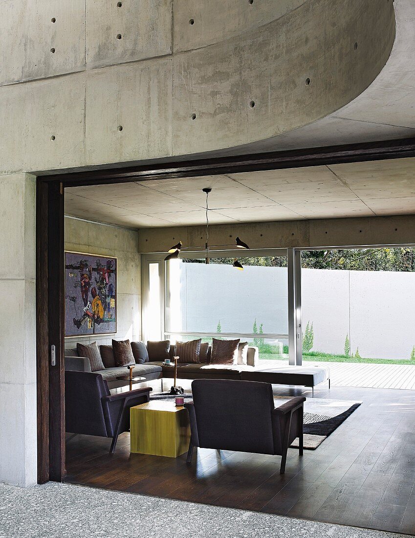 View into modern living room with concrete walls and glass wall