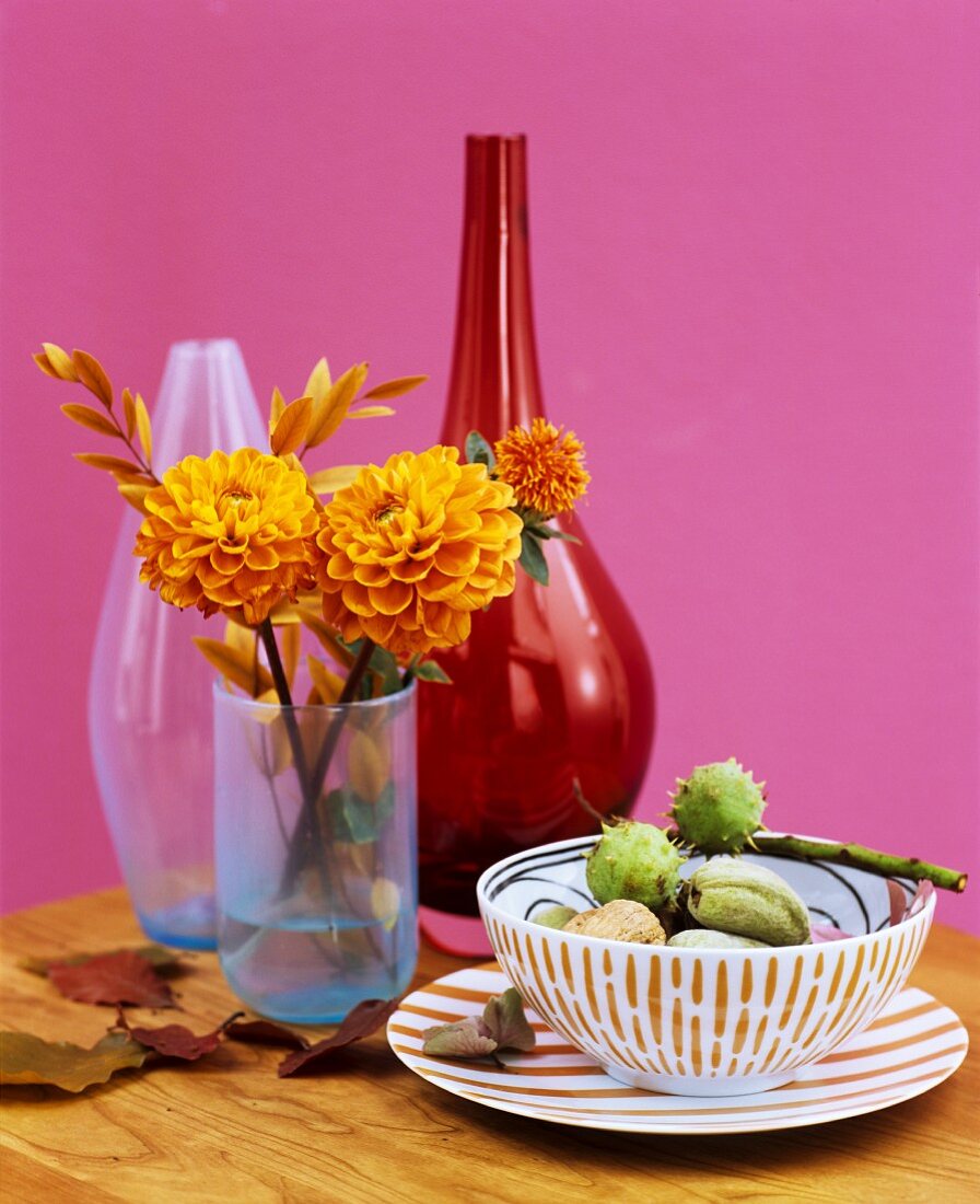 Crockery and vases decorated with autumnal dahlias and horse chestnuts