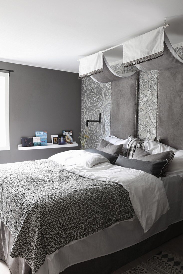 Elegantes Schlafzimmer in Grautönen, Grisaille edle Bettwäsche auf Doppelbett unter Baldachin mit glänzendem Stoff, Paneele an Wand