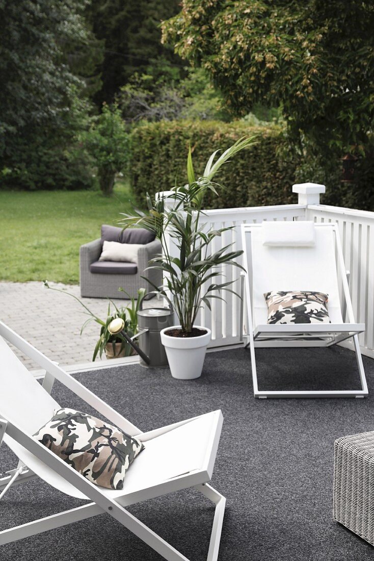 Wooden loungers with white seats on terrace with grey floor covering