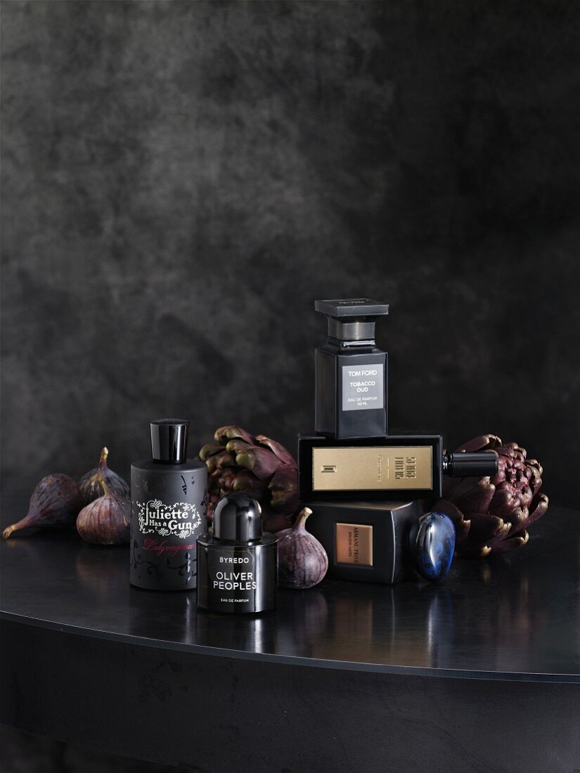 Schwarze Parfümflaschen mit Feigen und Artischocken als Gothic Deko auf einem Tisch