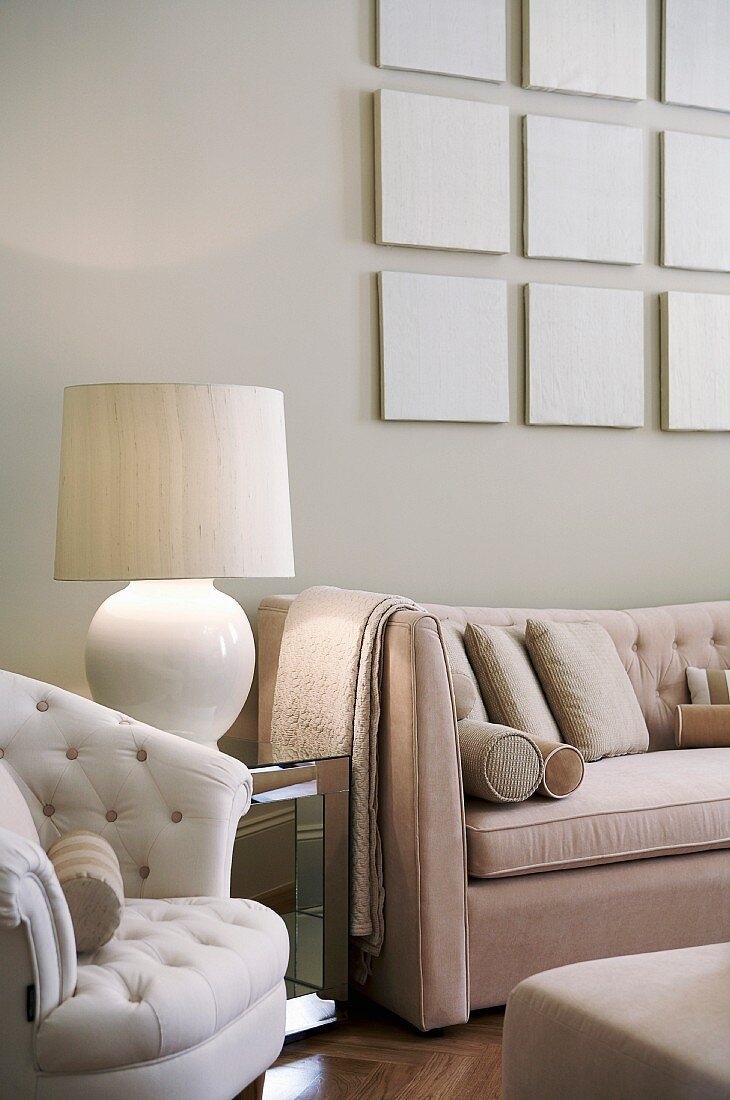 Grouping of pale, monochrome panels above sofa in pale beige living room