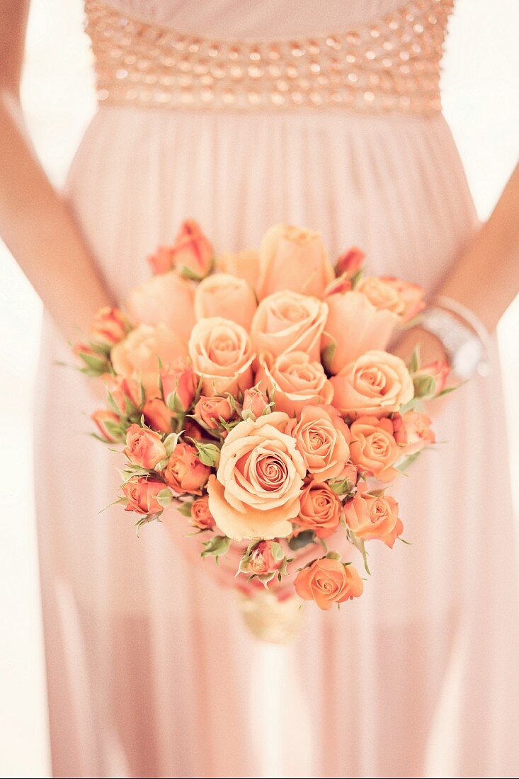 Romantischer Rosenstrauß vor Brautkleid in Händen gehalten