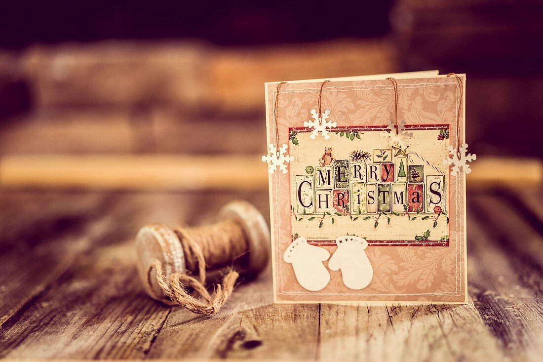 Weihnachtskarte mit Vintage Schnurrrolle auf rustikalem Holzuntergrund aufgestellt