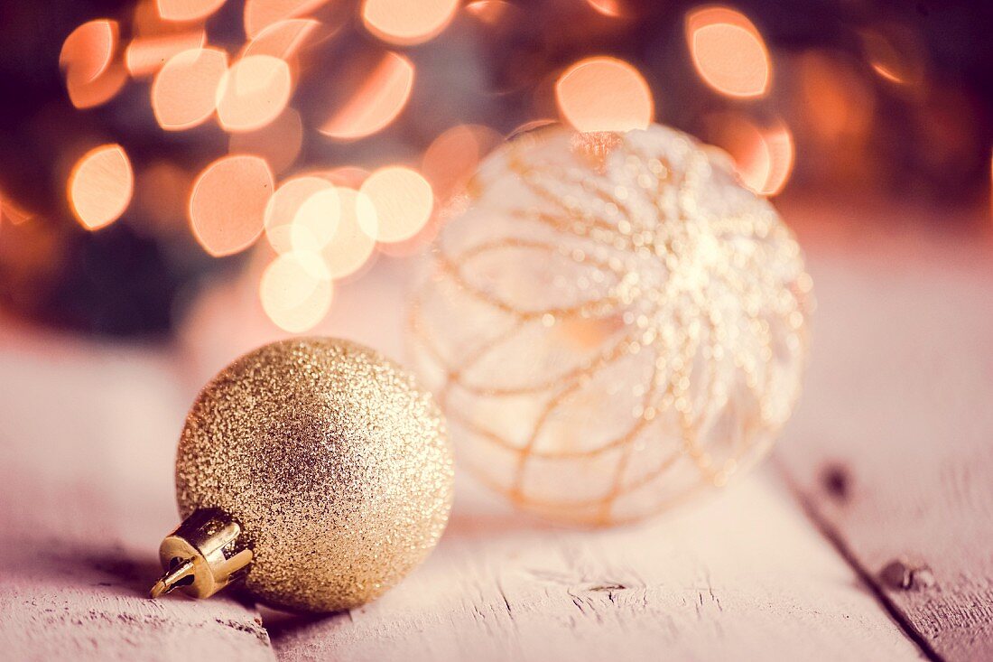 Lighting effects and gold baubles on rustic wooden surface
