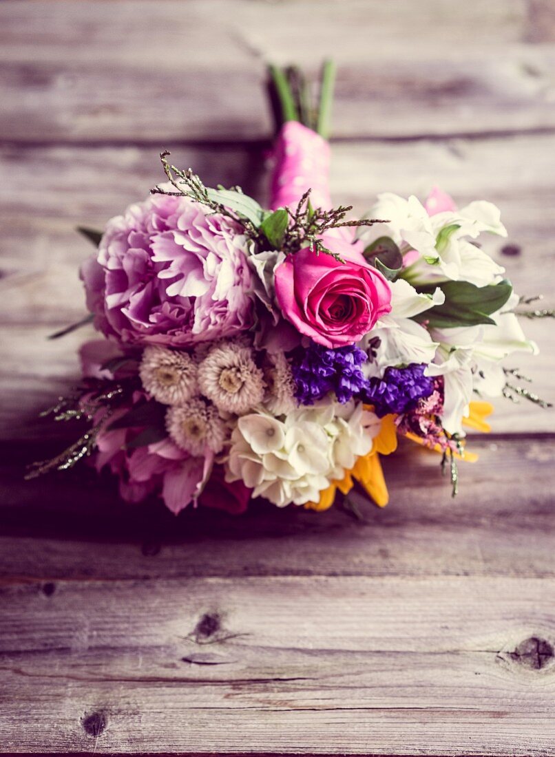 Garden bouquet of peonies, phlox and roses on rustic wooden surface