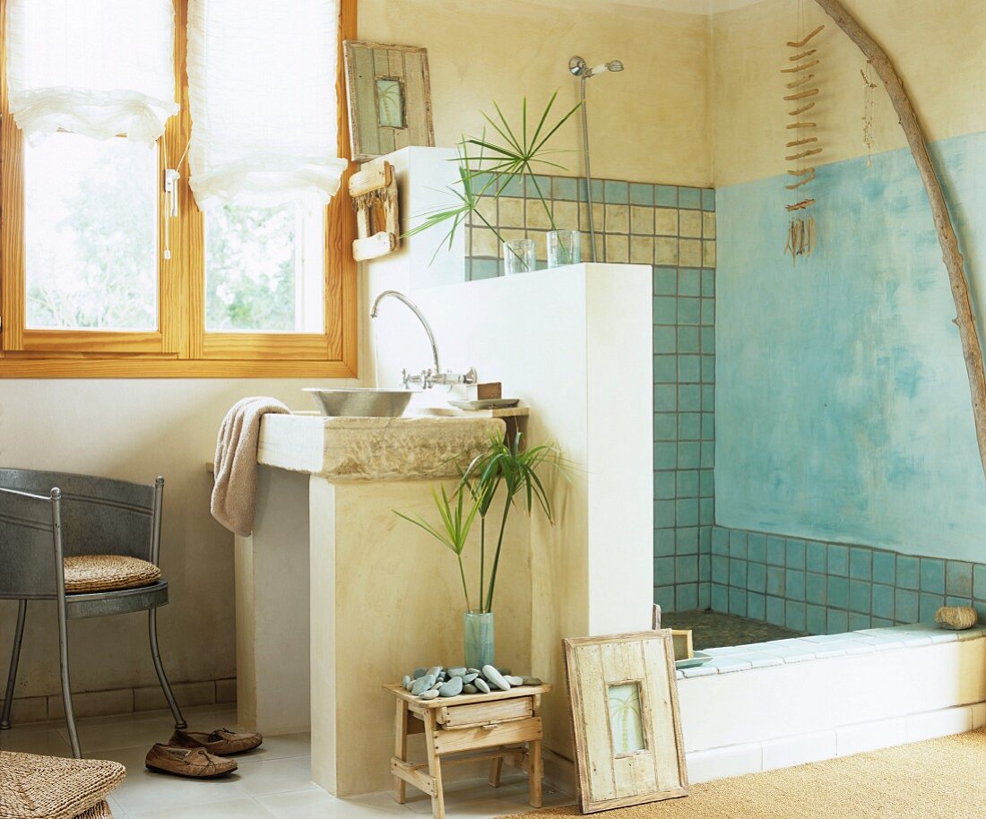 Bathroom with Mediterranean ambiance; masonry washstand against half-height partition wall screening shower with tiled wall and wall painted blue