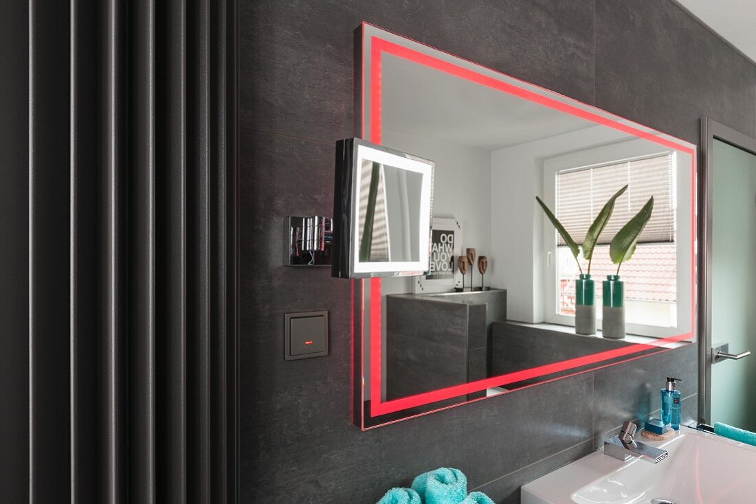 Wandspiegel mit integrierter LED Beleuchtung in Rot, an grau gefliester Wand