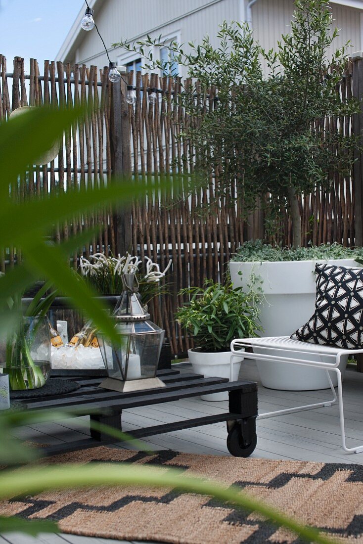 Terrasse mit Sichtschutz aus Ästen und einem Couchtisch aus einer Pallette