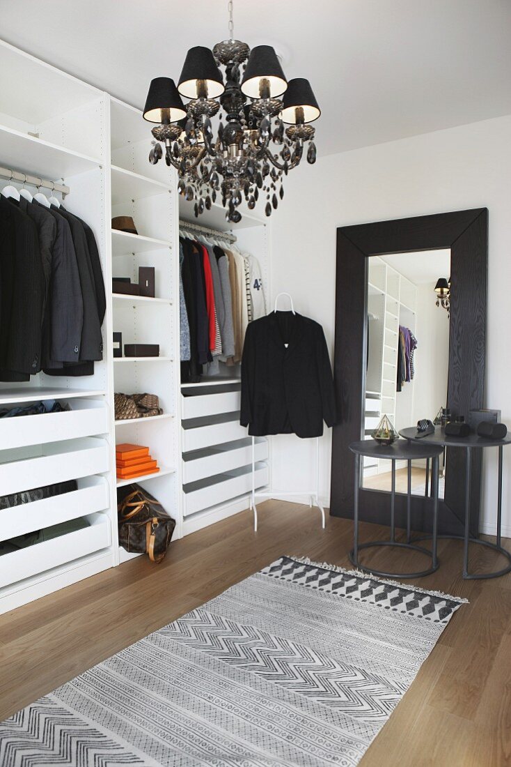 Open-fronted wardrobes, black chandelier and full-length mirror in dressing room