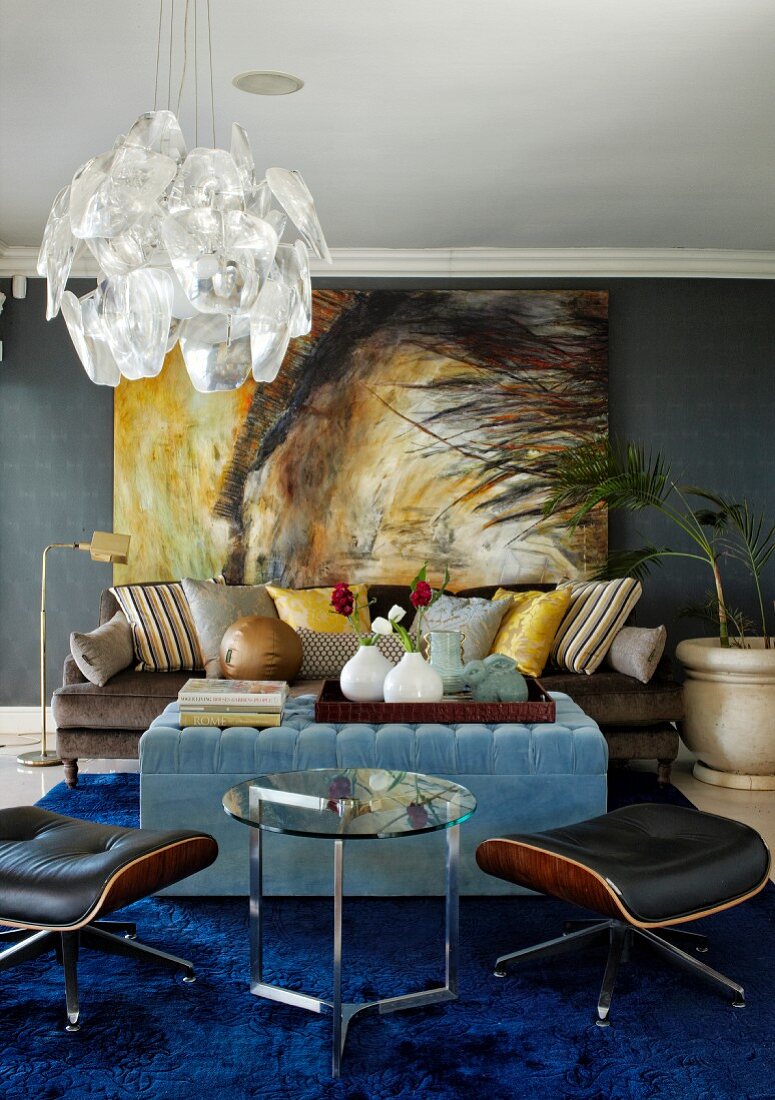 Dramatisches Gemälde an dunkelgrauer Wand im Wohnzimmer mit hellblauem Polstertisch und Designklassikern