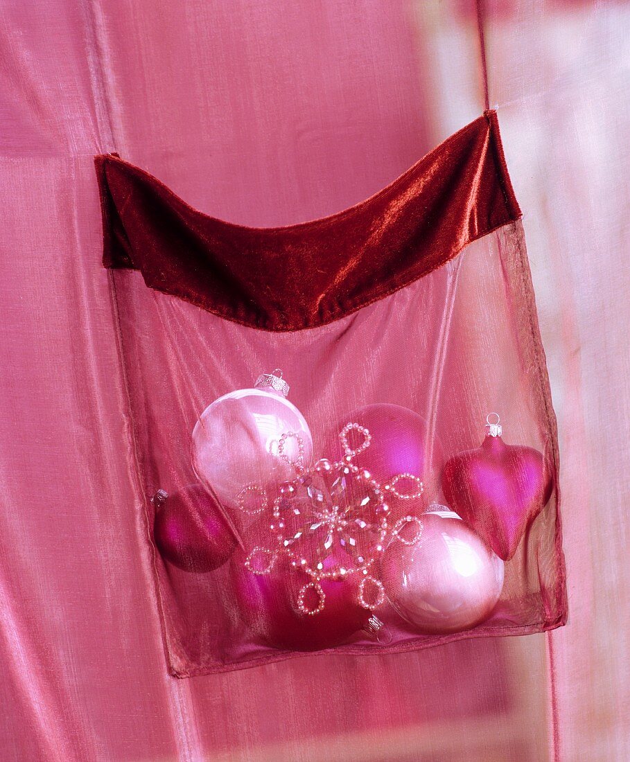 Christmas tree baubles in pocket on pink, chiffon curtain
