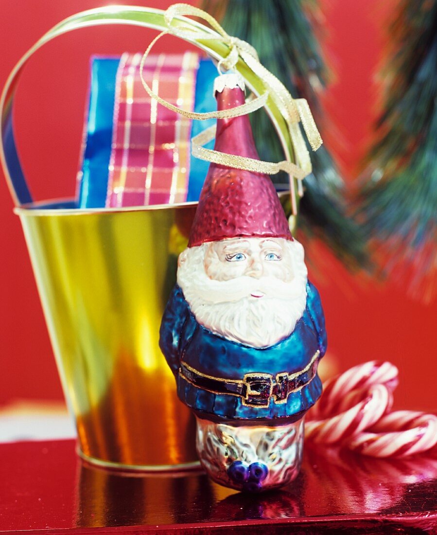 Christmas arrangement of Father Christmas bauble & gift in golden bucket