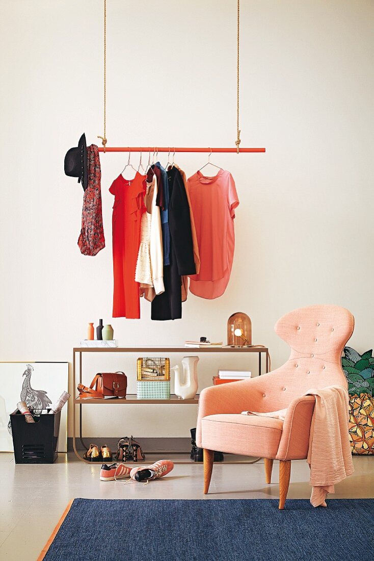 Women's clothing hanging from a floating red clothes rail with an open shelf in a retro room