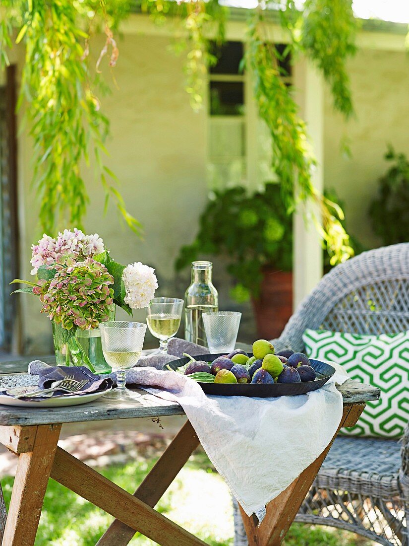 Gartentisch mit Weißwein und Früchten