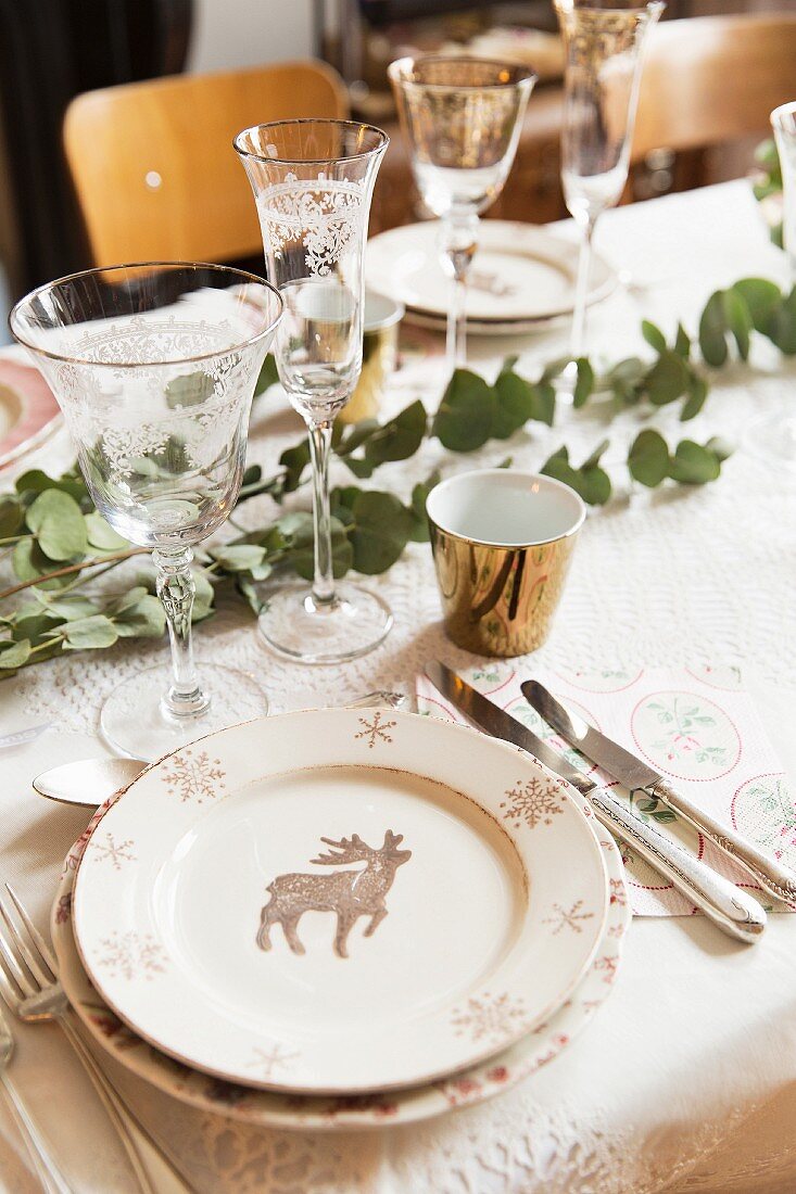 Weihnachtlich gedeckter Tisch mit Eukalyptuszweigen und Tellern mit Hirschmotiv