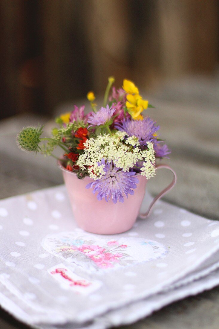 Cup of wild flowers on rustic napkin