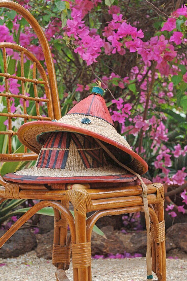 Bemalte Strohhüte auf Bambusstuhl im Freien