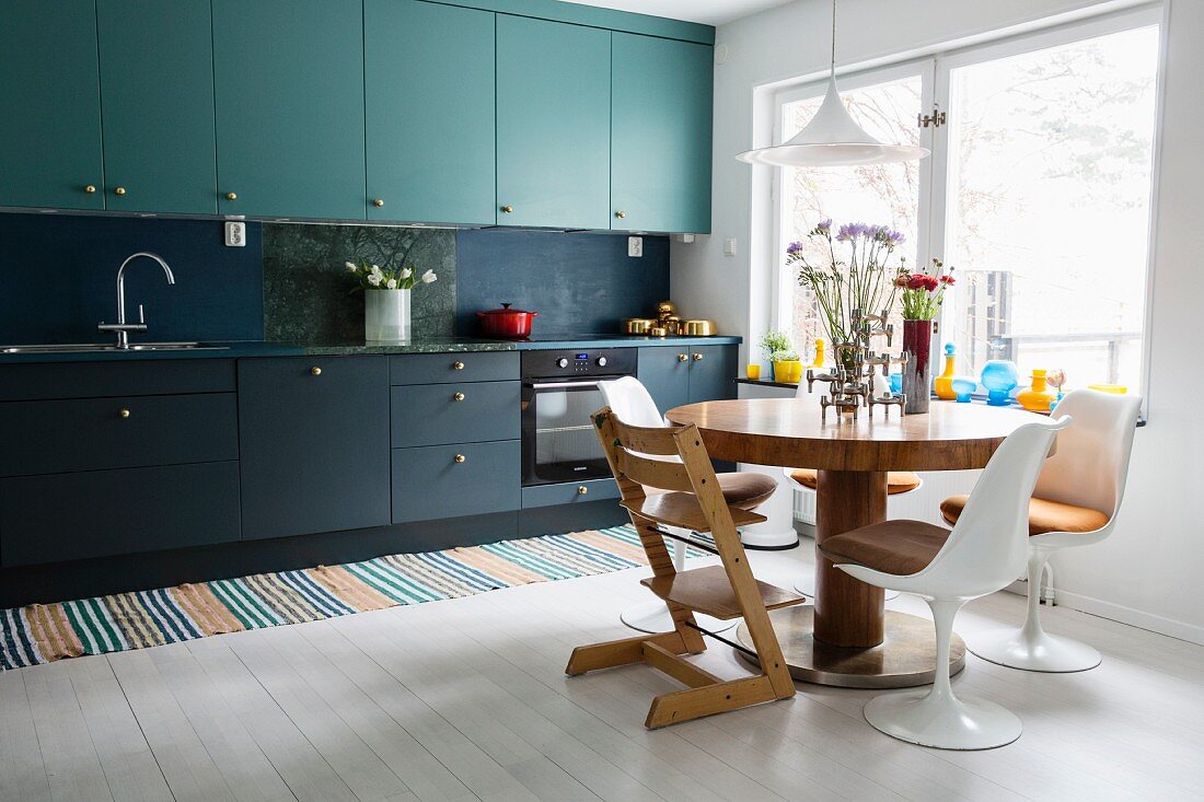 Küche mit zweifarbigen Fronten und rundem Esstisch mit Designerstühlen