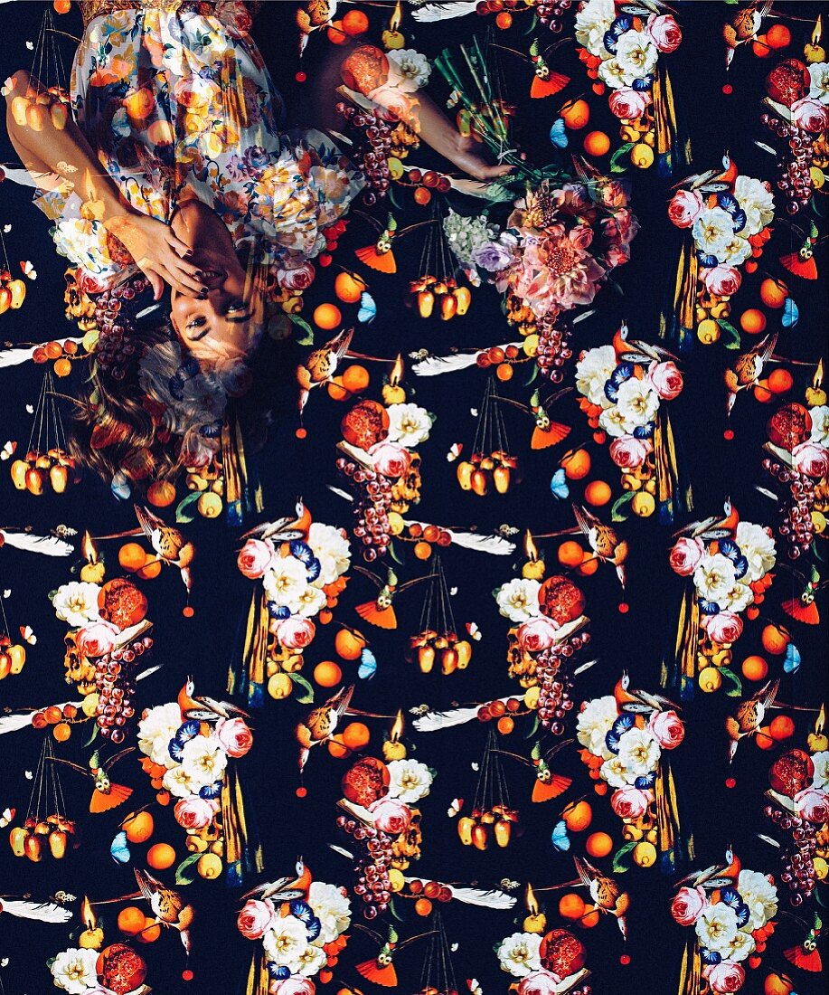Junge Frau auf einer Tapete mit dunklem Muster aus Blumen und Früchten