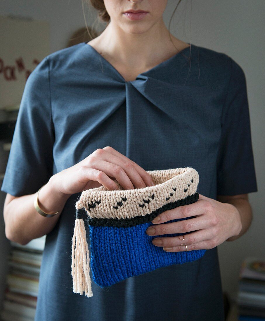 A woman holding a knooked clutch bag – knitting with a hook