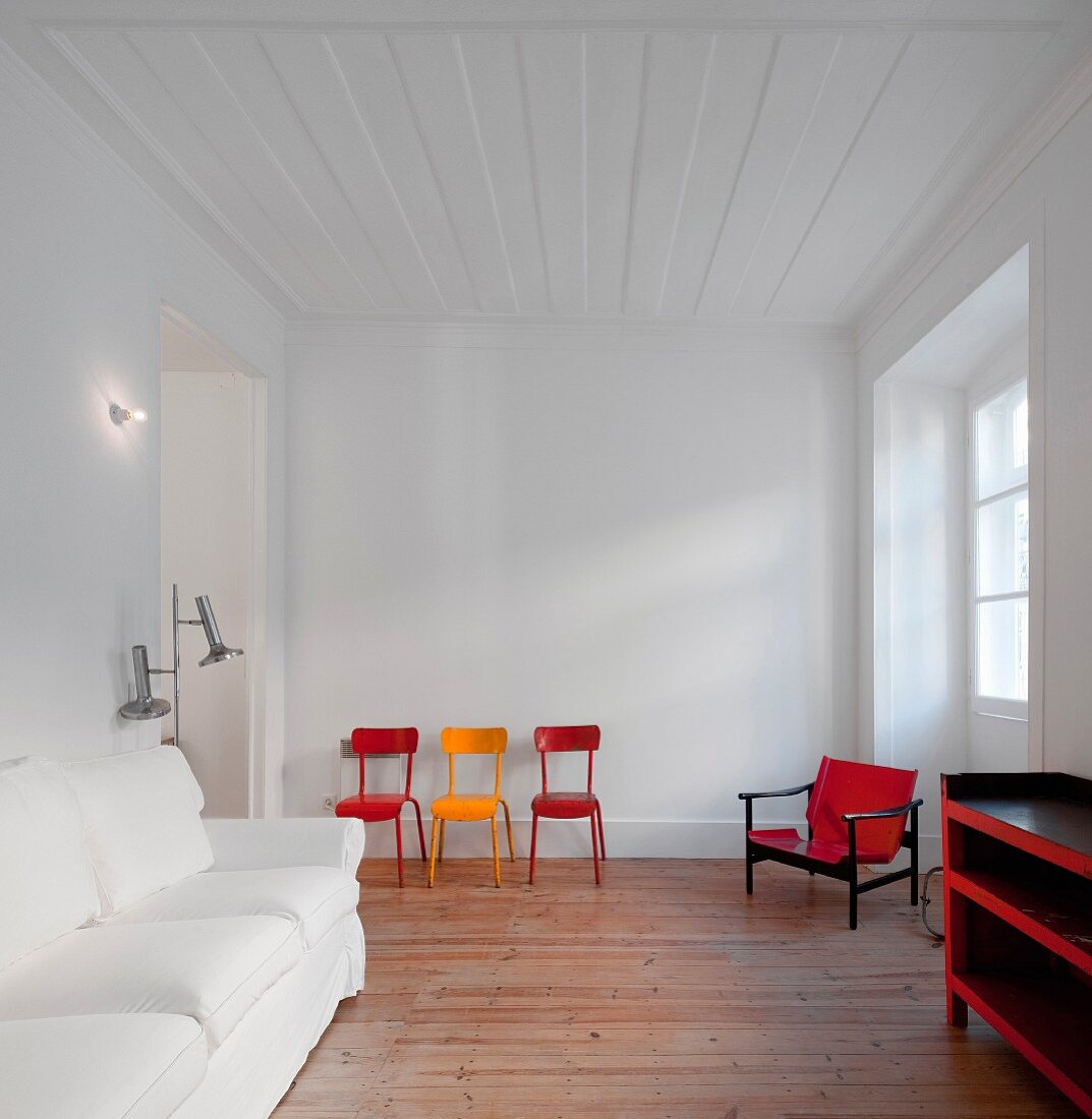 Weisses Wohnzimmer mit farbigen Retro Stühlen und Sessel