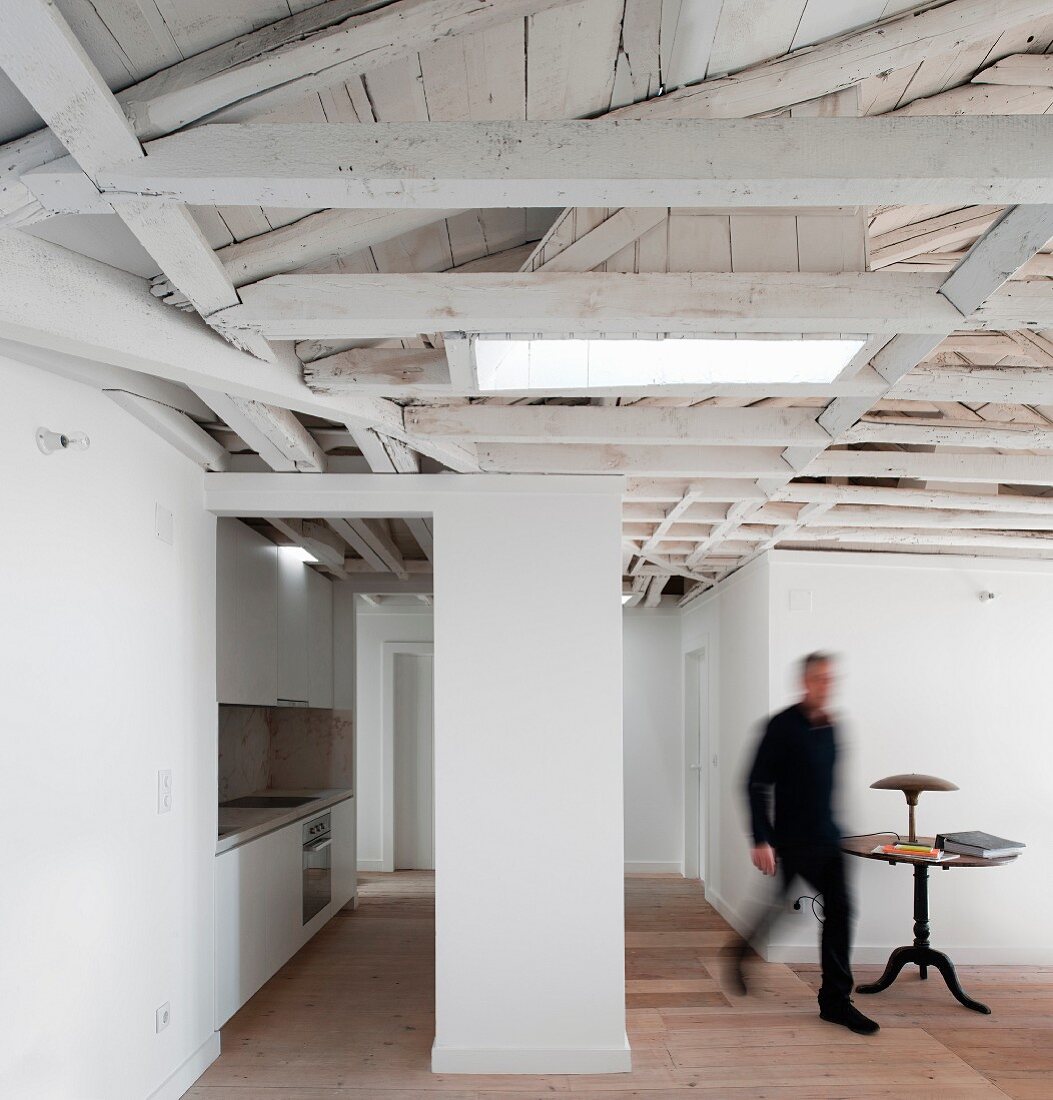 Attic with exposed, white-painted roof structure and fitted kitchen to one side
