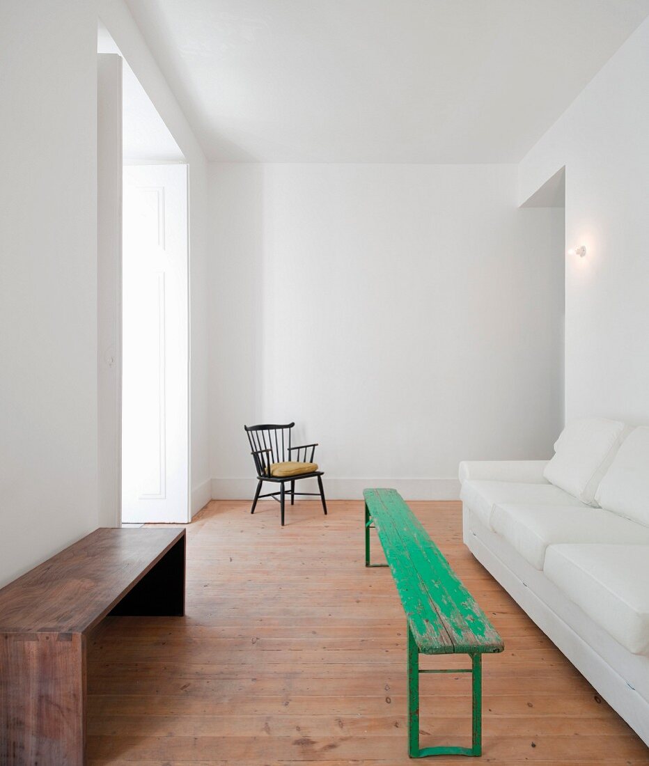 Interior with green-painted bench between wooden bench and white sofa