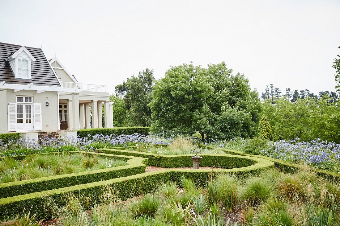 Geometrisch angelegter Garten mit Hecken und elegantem Landhaus
