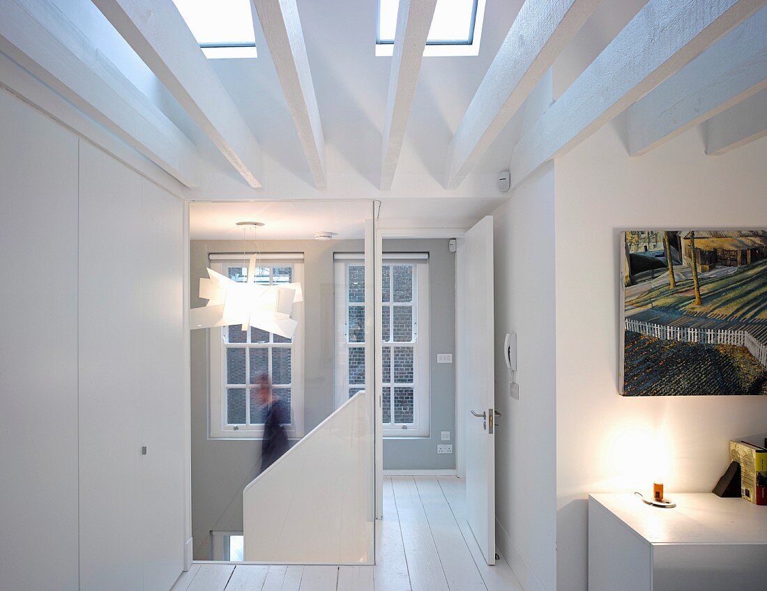 Heller Dachgeschoss Flurbereich mit weißen Holzbalken und darüberliegenden Oberlichtern, offene Tür zum Treppenraum