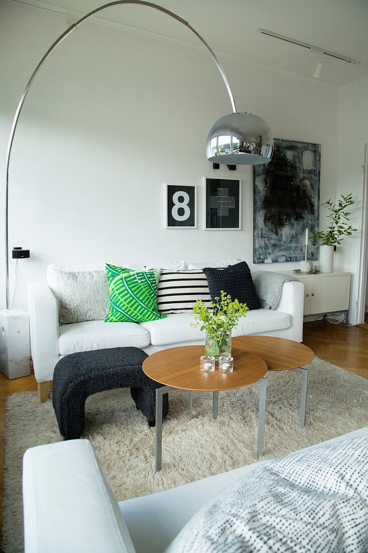 Wohnzimmer mit Sofas und runden Beistelltischen auf Hochflorteppich, italienische Klassikerleuchte aus den 60er Jahren