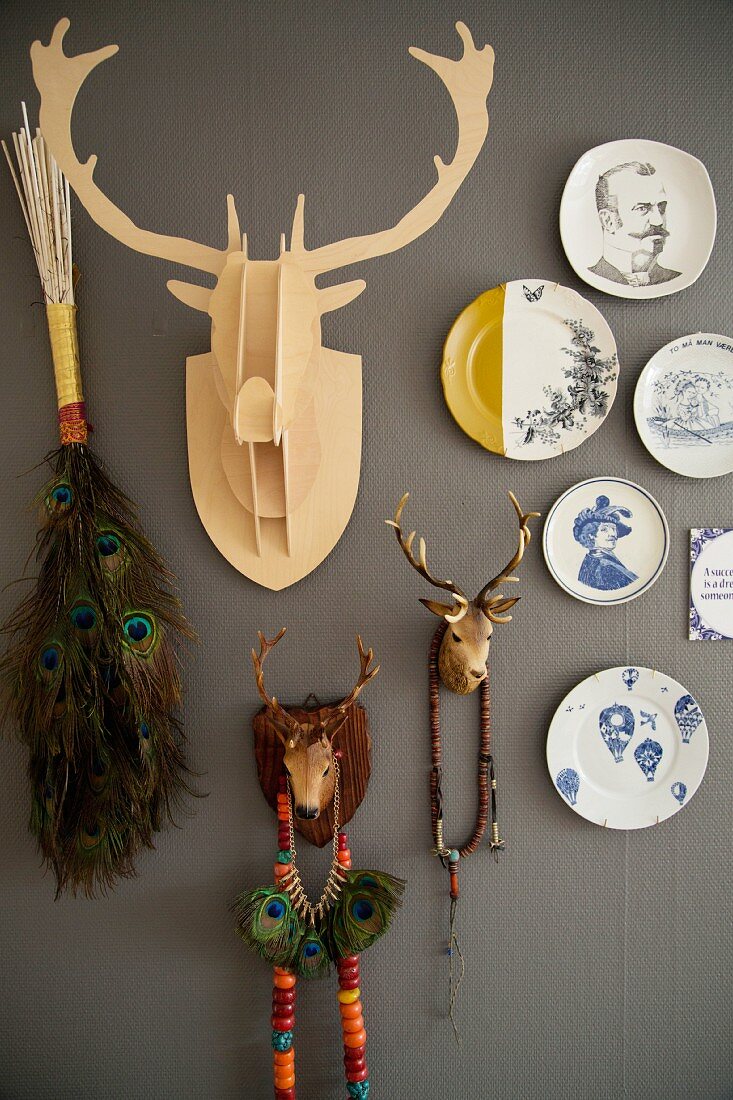 Decorative wall plates and various hunting trophies on dark grey wall