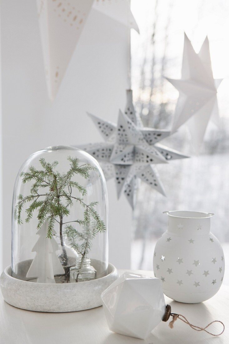 weiße Weihnachtsdeko mit Tannenzweig unter Glasglocke