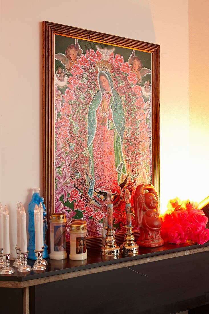 A shrine on a dark surface with a framed religious picture on the wall