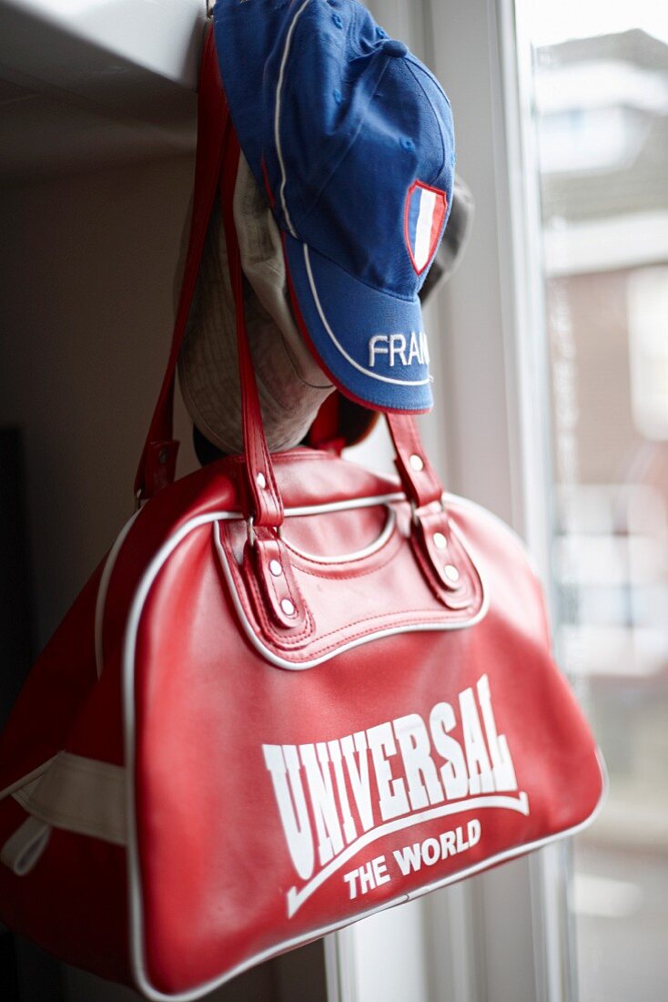 Red sports bag and blue cap hanging from peg