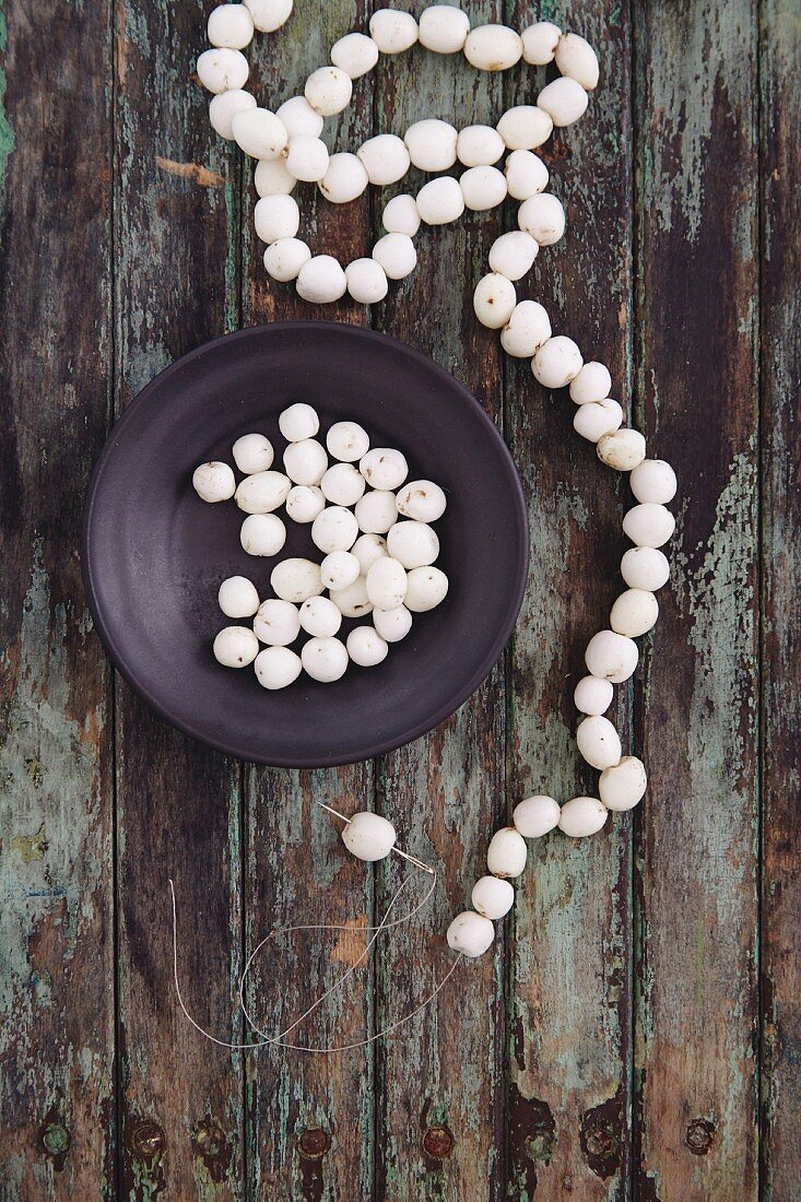 A necklace being made from snowberries