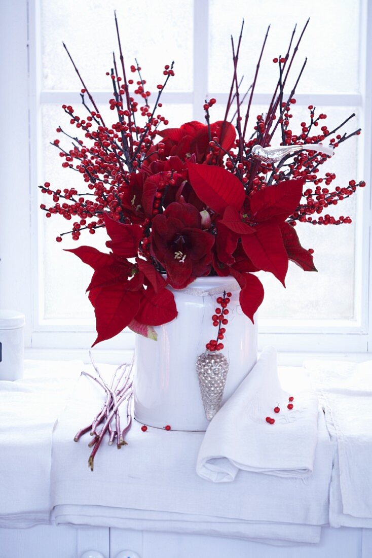 A red winter arrangement of holly berries, amarillis and poinsettias