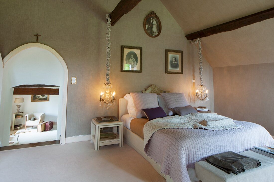 Ländliches Schlafzimmer, leuchtende Hängelampen neben Doppelbett, seitlich offene Rundbogentür