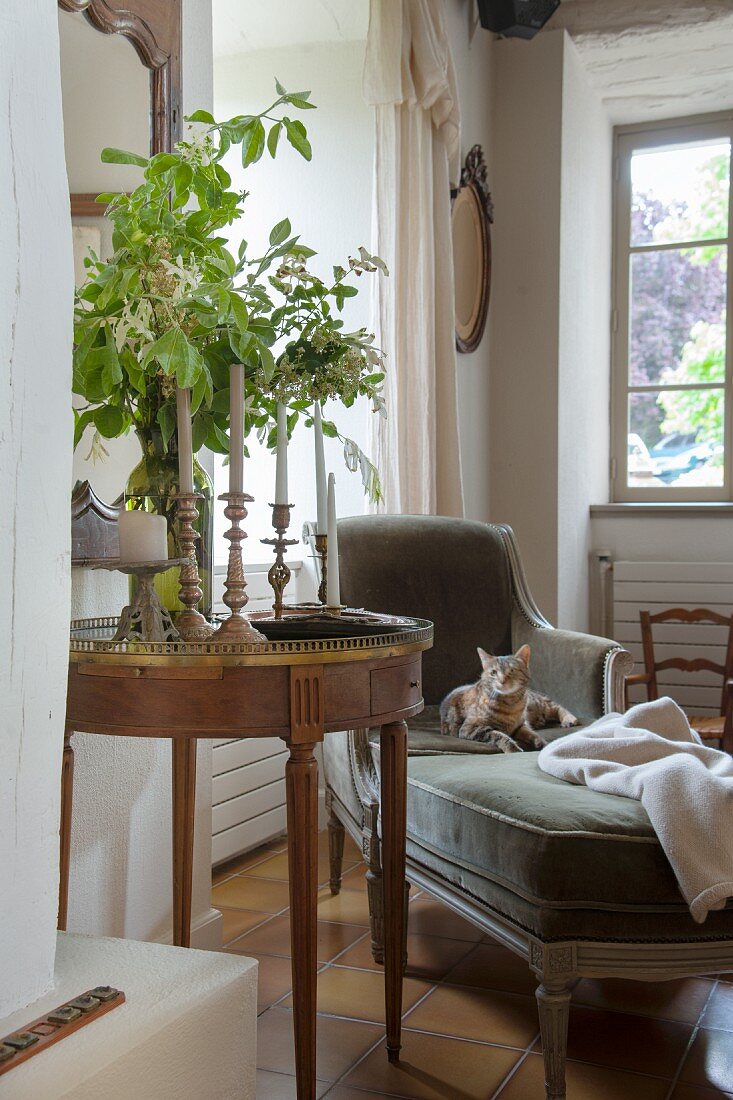 Biedermeier Beistelltisch mit Kerzenständern, daneben Chaiselongue vor Fenster