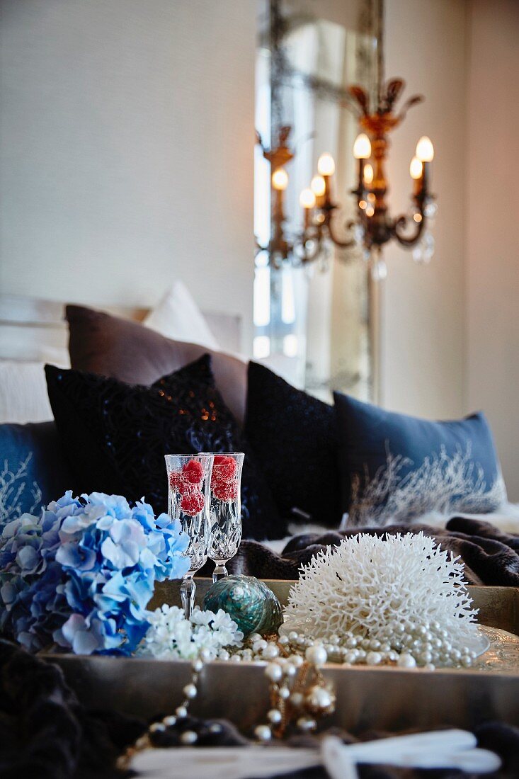 Blaue Hortensienblüte, Sektgläser, Koralle und Perlenkette auf Tablett, im Schlafzimmer