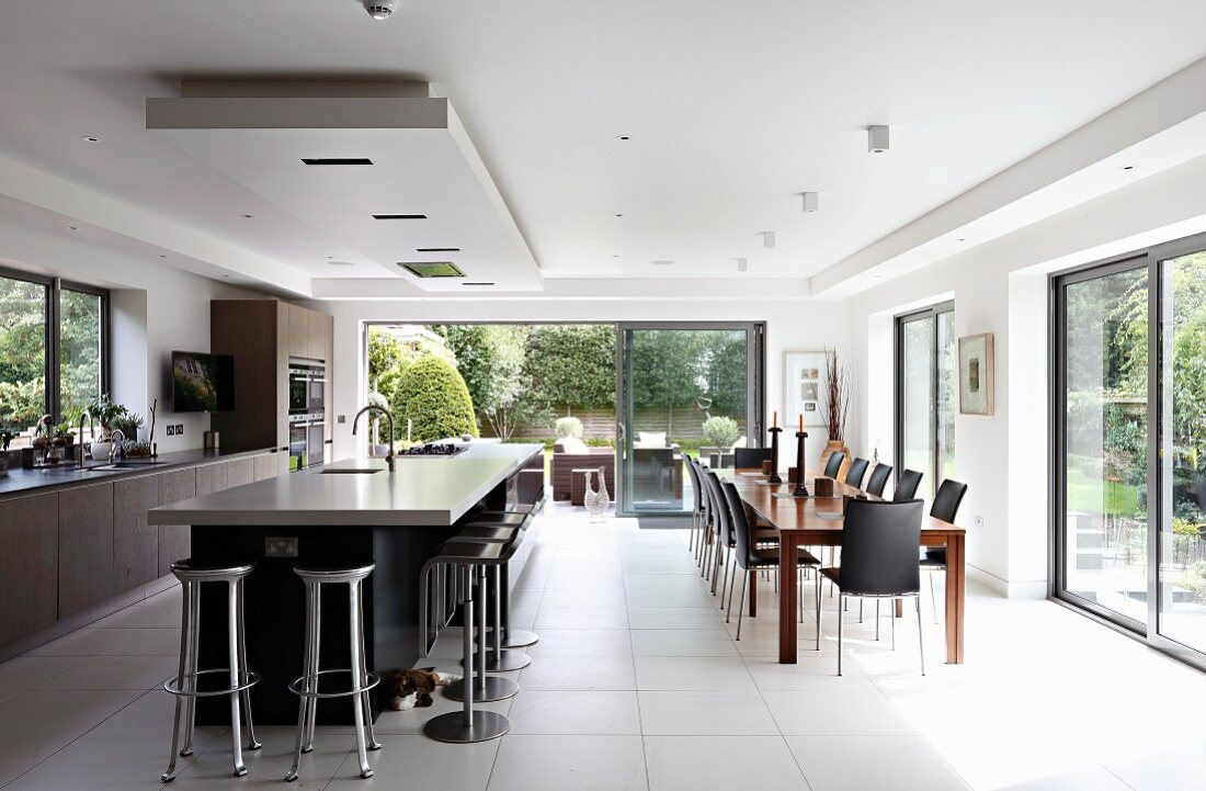 Island counter below suspended ceiling section and spacious dining area in modern, open-plan kitchen