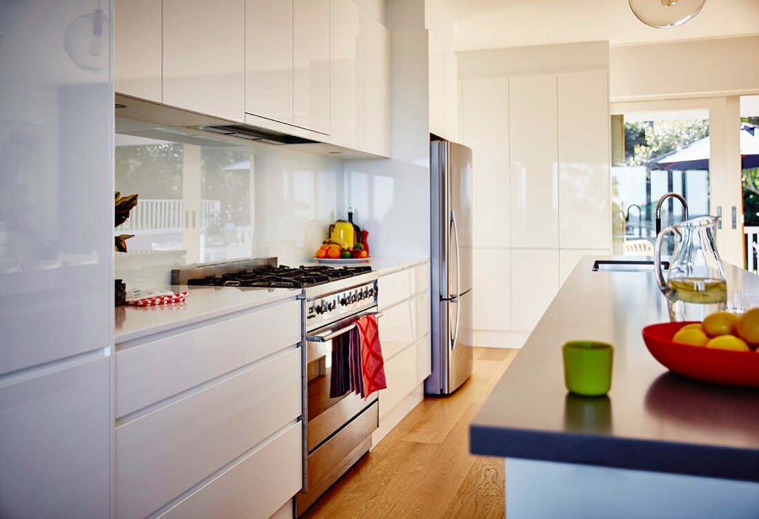 Free-standing counter opposite fitted kitchen counter with white wall-mounted and base units