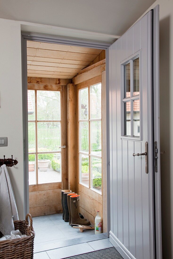 Open front door painted grey with view onto wood-clad porch with lattice windows