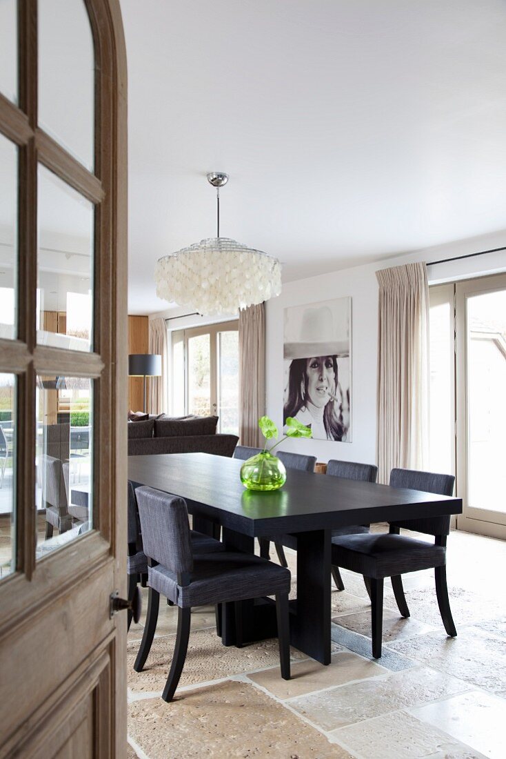 Blick durch offene Tür auf Wohnzimmer mit schwarzem Esstisch und Stühlen