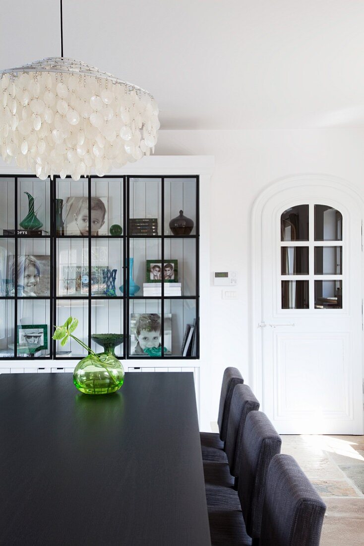 Black and white dining room with capiz shell lampshade and family photos in display cabinet